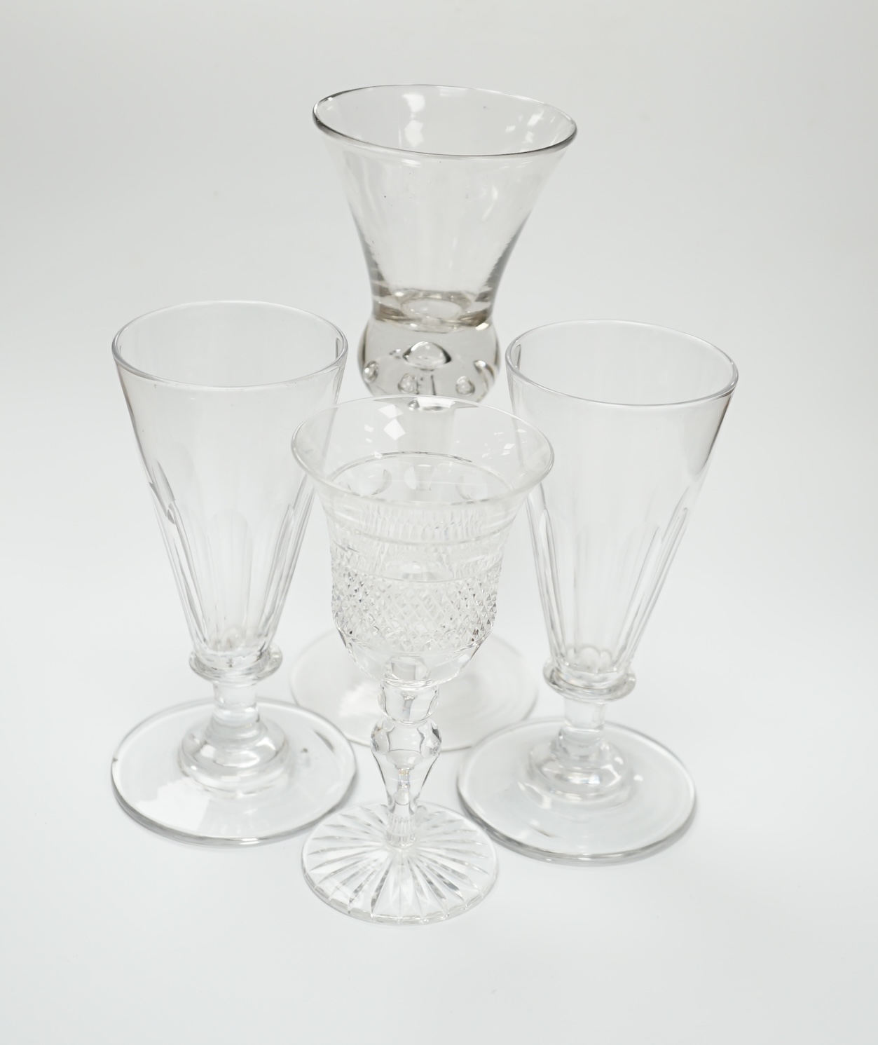 A pair of early 19th century dwarf ale glasses with fluted conical bowls, bladed knop stems and polished pontils, together with a mid-18th century thistle bowl glass with multiple air tears, plain stem and domed foot and